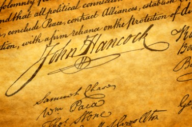 An antique close up image of John Hancock's famous large script signature on historical parchment.